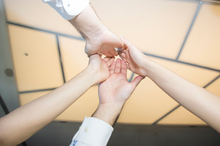 Three people are holding hands in a circle, symbolizing unity and teamwork