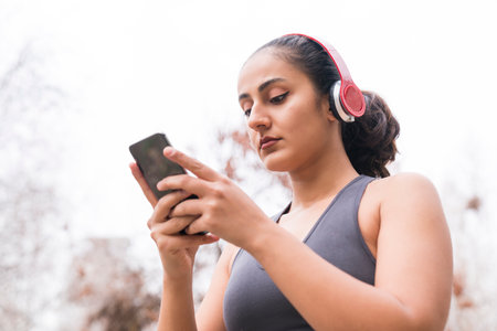 Young woman checking fitness tracker after workout. Fitness concept with earphones and smartphone.の写真素材
