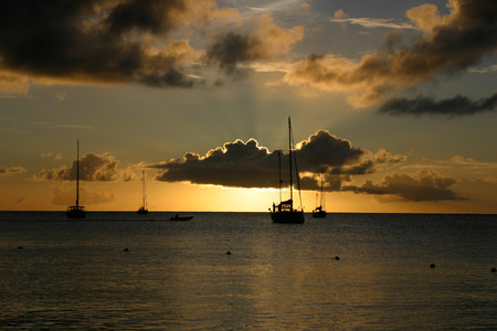 Sailing boats and clouds silhouetted against a fading sun.  Rodney Bay, St Lucia.の写真素材