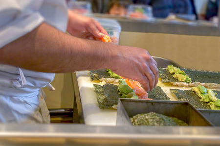 A sushi chef preparing Uramaki with avocado and salmonの写真素材