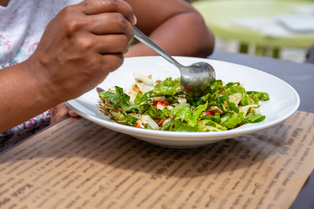 A young woman eating a fresh salad in the sunshineの写真素材