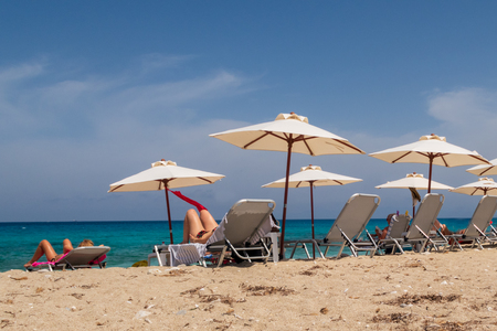 Tourists relaxing on sun loungers on the beach on Lefkada island, Greeceの写真素材