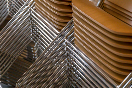 Stacked chairs with wooden seats and metallic legsの写真素材