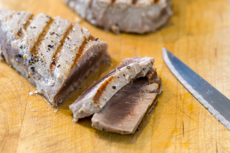 Chargrilled, seasoned tuna steaks cooked and sliced on a wooden chopping boardの写真素材