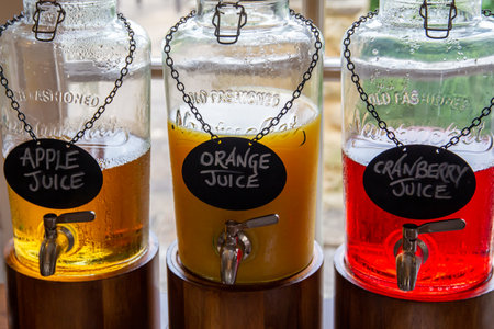 KETTERING, ENGLAND - JUNE 24 2019: Variety of glass breakfast juice dispensers for orange, apple and cranberry juiceのeditorial素材