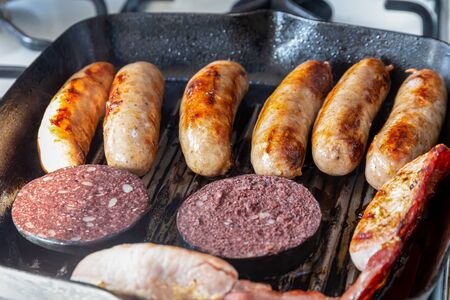 Cumberland sausages, back bacon and black pudding cooking in a griddle panの写真素材