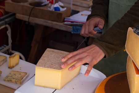 Market stall worker slicing cheese with a wire cheese cutterの写真素材