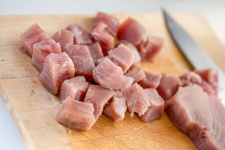 Fresh raw tuna steaks, cut into chunks on a wooden chopping boardの写真素材