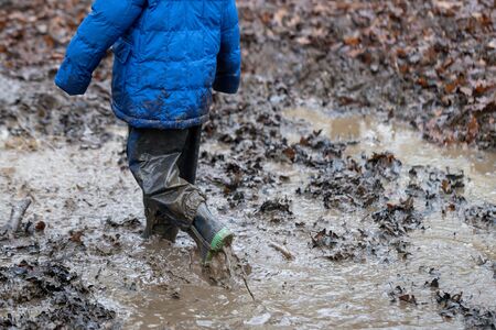 Young children playing in a muddy puddle