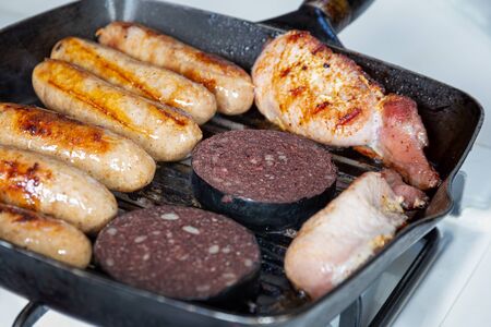 Cumberland sausages, back bacon and black pudding cooking in a griddle panの写真素材