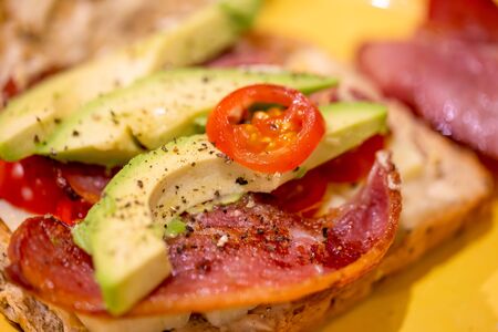 Bacon, avocado, cheese and tomato open sandwichの写真素材