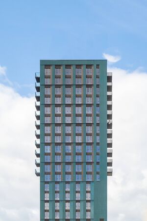 Block of modern apartments with balconies against a blue sky background