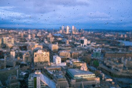 Raindrops on a window pane of glass with blurred background of River Thames and City of London Canary Wharf financial districtの写真素材