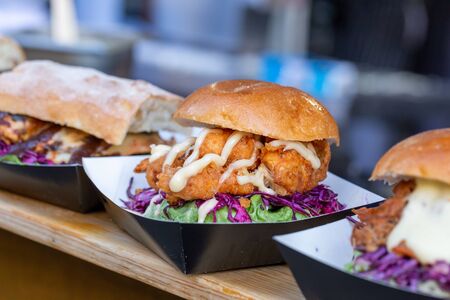 Variety of gourmet chicken burgers displayed on a food market stallの写真素材