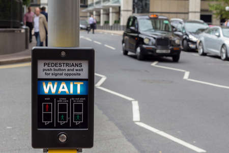 Illuminated Wait pedestrian sign at a pedestrian crossing on a busy road in central London, England