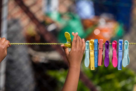 A young african american child playing with clothes pegs and a washing line in the gardenの写真素材