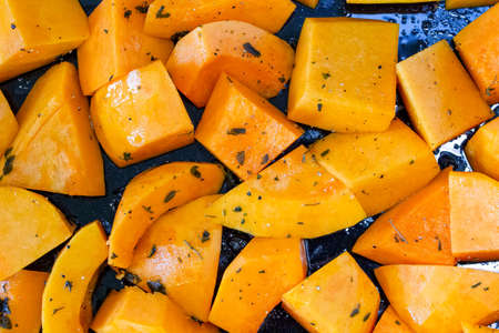 Close up of butternut squash chunks prepared for roasting, on a baking trayの写真素材