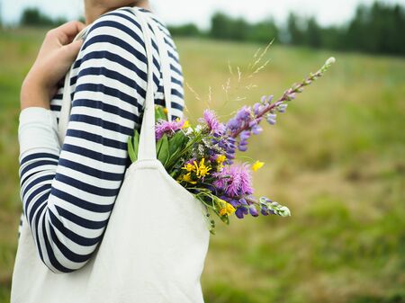 young beautiful girl holding a bag with wildflowersの写真素材