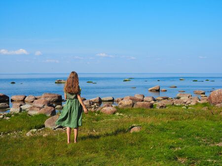 young beautiful girl happy in the background of the sea rear viewの写真素材