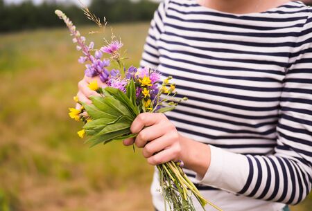 young beautiful girl holding a bouquet of wild flowersの写真素材