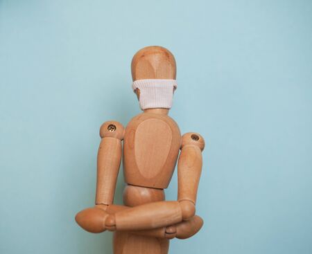 Wooden mannequin in the mask from the coronavirus