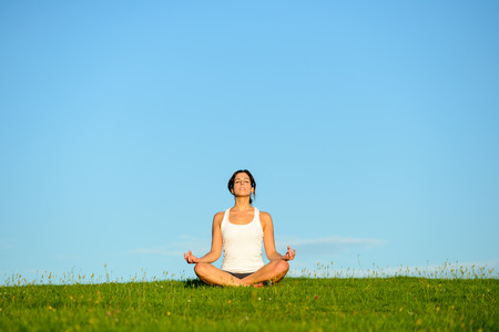 Young woman doing yoga relaxing and breathing exercise outdoor. Relax and tranquility at green grass field towards blue clear sky. Young woman doing yoga relaxing and breathing exercise outdoor. Relax and tranquility at green grass field towards blue clear sky.