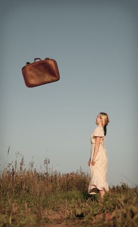 Beautiful woman looks at the falling suitcaseの写真素材