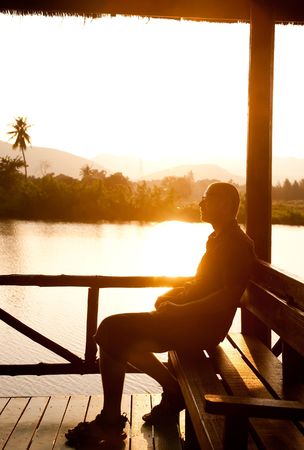 Young man relaxing in summerhouse at riverside.の写真素材