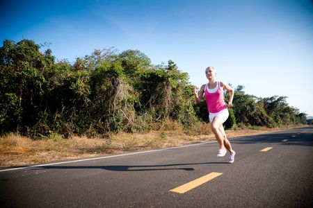 Blond young woman running cross country. Subject is blurred due to motion.の写真素材