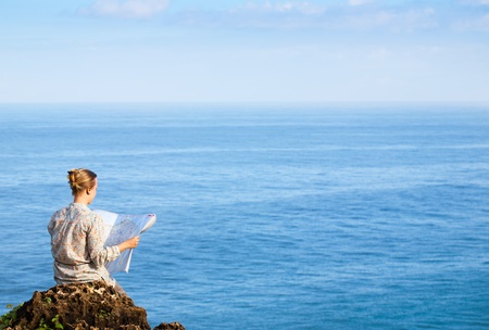 Woman reading map near the seaの写真素材