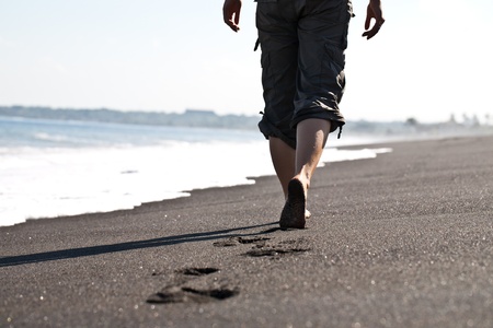 Woman walking on the black sand beachの写真素材