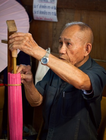 CHIANG MAI, THAILAND - FEBRUARY 5: Senior man making a wooden umbrella in traditional umbrella factory on February 5, 2012 in Chiang Mai, Thailandのeditorial素材