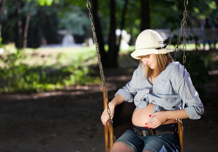Beautiful pregnant woman sitting on a swing の写真素材