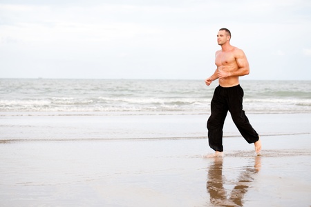 Physically fit man running on the beachの写真素材