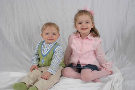 Brother and sister sitting together on white backgroundの写真素材