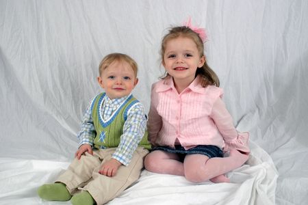 Brother and sister sitting together on white backgroundの写真素材