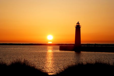 Sun setting over lake near lighthouse.の写真素材