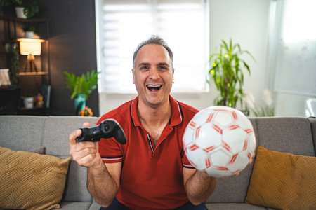Middle age Caucasian man playing soccer video game at homeの写真素材