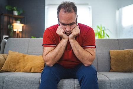 Man sitting alone at home looking sad and distraughtの写真素材