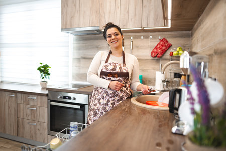 Happy woman wearing apron in the kitchenの写真素材