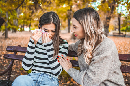 Two women are sitting on a bench and comforting each other
