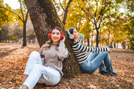 Woman Sitting Next to Tree Wearing Headphonesの写真素材