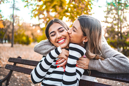 Two Women Kissing and hugging on a Park Benchの写真素材