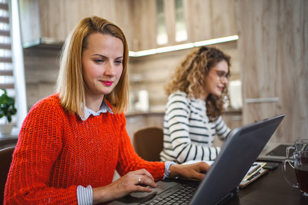 Two female colleagues at a desk working on laptopの写真素材