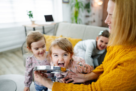 Mother spending time with her three little daughters at homeの写真素材