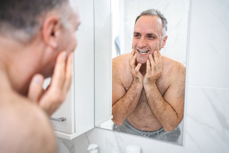Man washes himself after shaving in the bathroomの写真素材