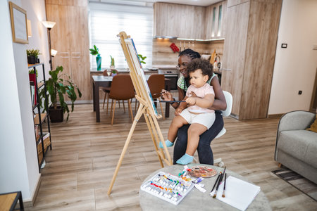 Mom and child happily paint in a cozy kitchenの写真素材
