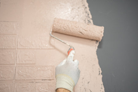 Person Painting a Brick Wall With a Paint Rollerの写真素材