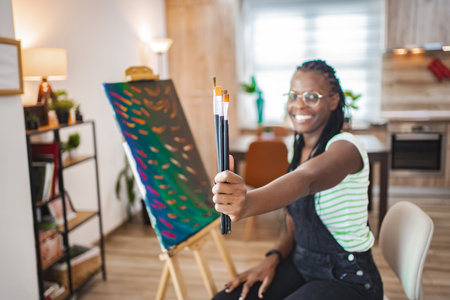 Creative artist showcasing paintbrushes in a bright studioの写真素材