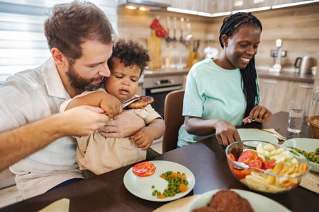 Family enjoying a meal together in a cozy kitchen at homeの写真素材